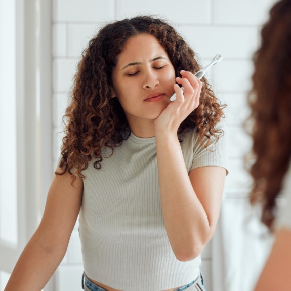 Frau hat Zahnschmerzen beim Zähneputzen