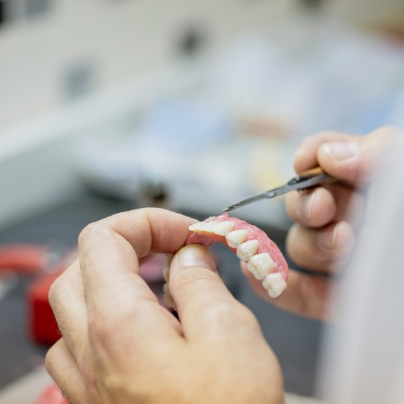 Person arbeitet an einem Zahnarsatzmodell