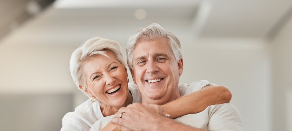 Älteres Pärchen umart sich lachend auf Couch