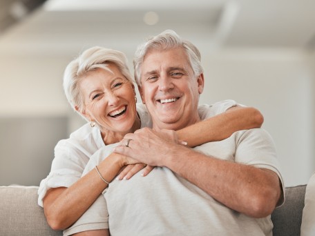 Älteres Pärchen umart sich lachend auf Couch