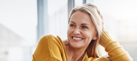 Frau stütz sich auf Sofalehne und Lacht