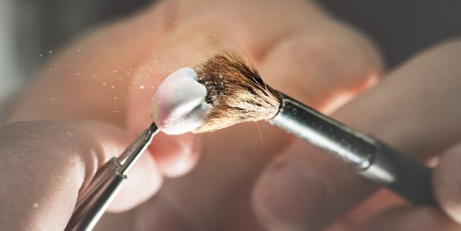 Person säubert eine unfertige Zahnprothese mit einem Pinsel