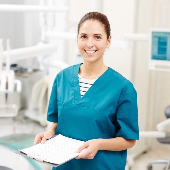 Zahnmedizinische Fachangestellte mit Klemmbrett lächelt